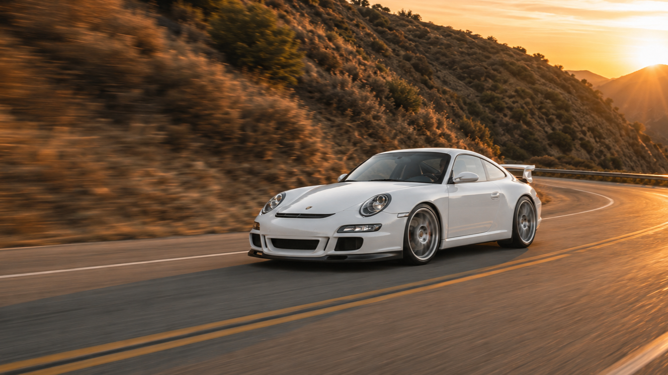 White Porsche 997 GT3 on a winding canyon road at golden hour